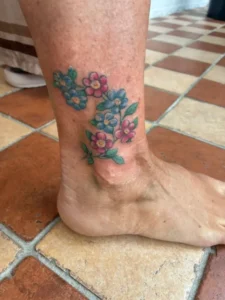 Kleurige bloemen op enkel tattoo